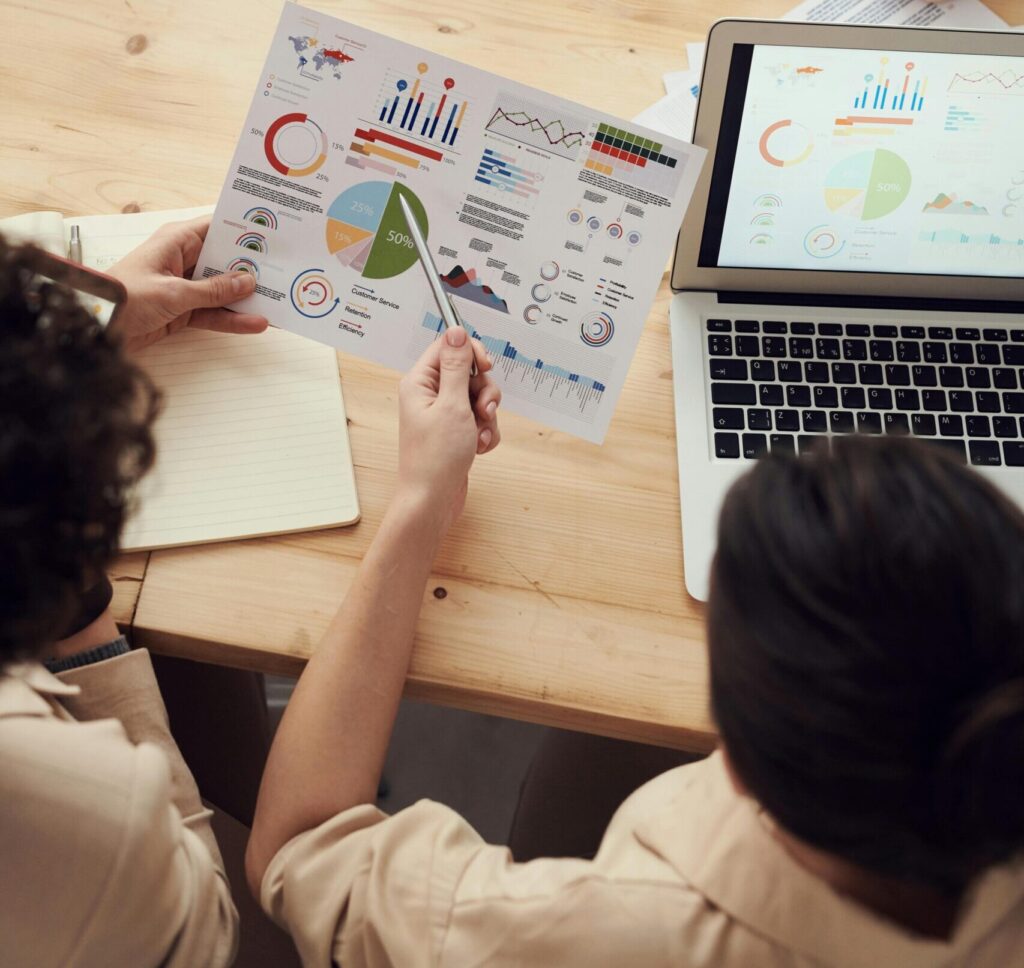 Colleagues collaborate on data analysis at a team meeting with charts and laptop.